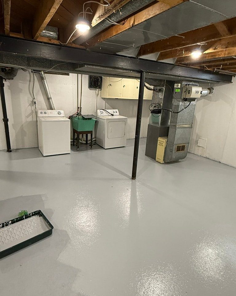 Unfinished basement ceiling with exposed wooden joists and a black painted steel beam.