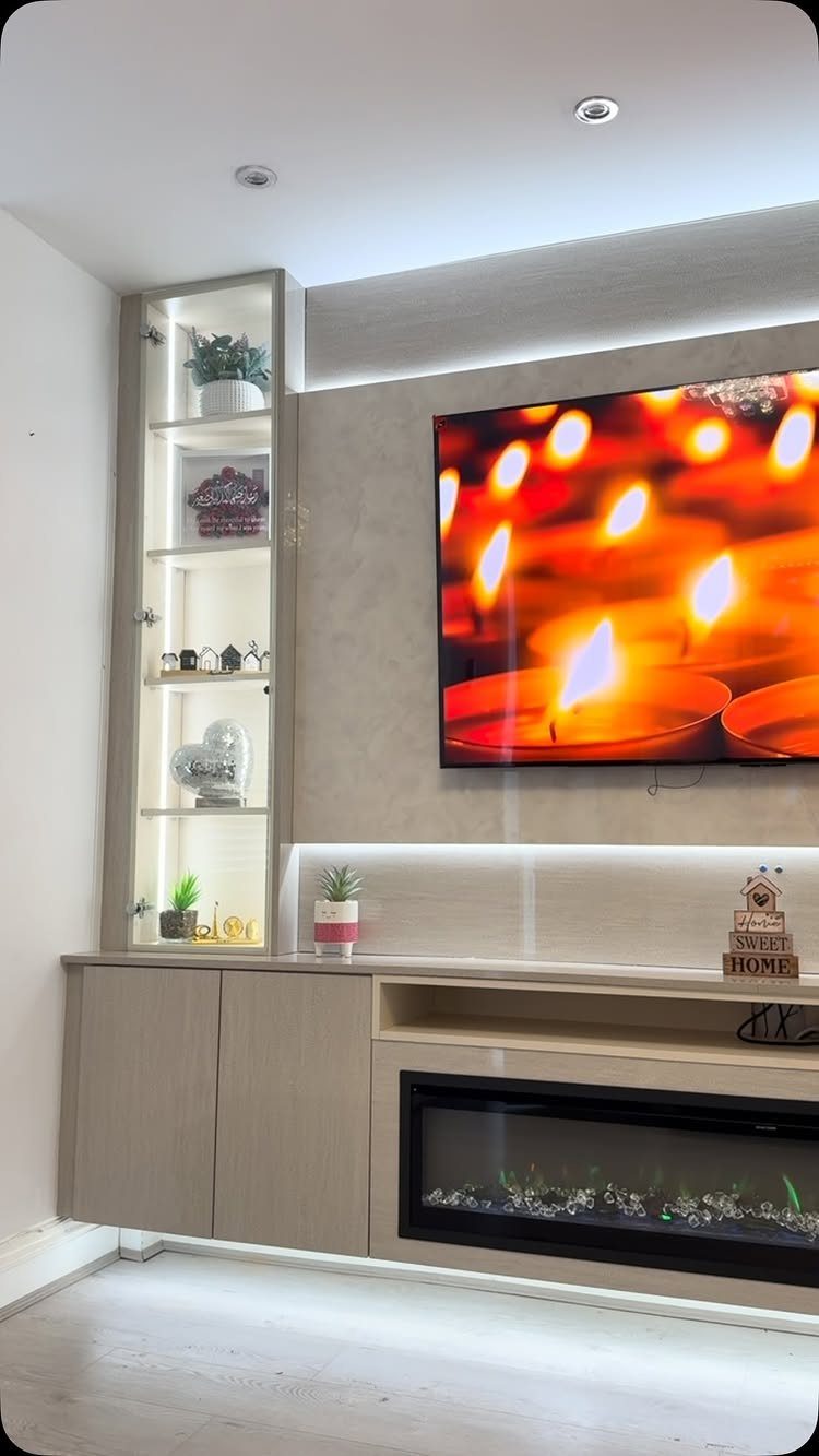 Modern wall TV unit with backlit panels, integrated electric fireplace, and glass display cabinet.