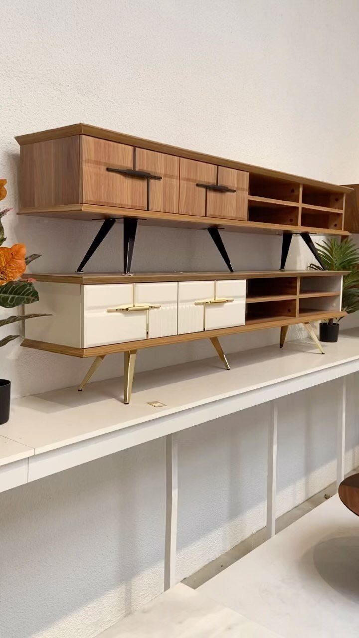 Two mid-century modern TV consoles with cabinets and open shelving on a white platform.