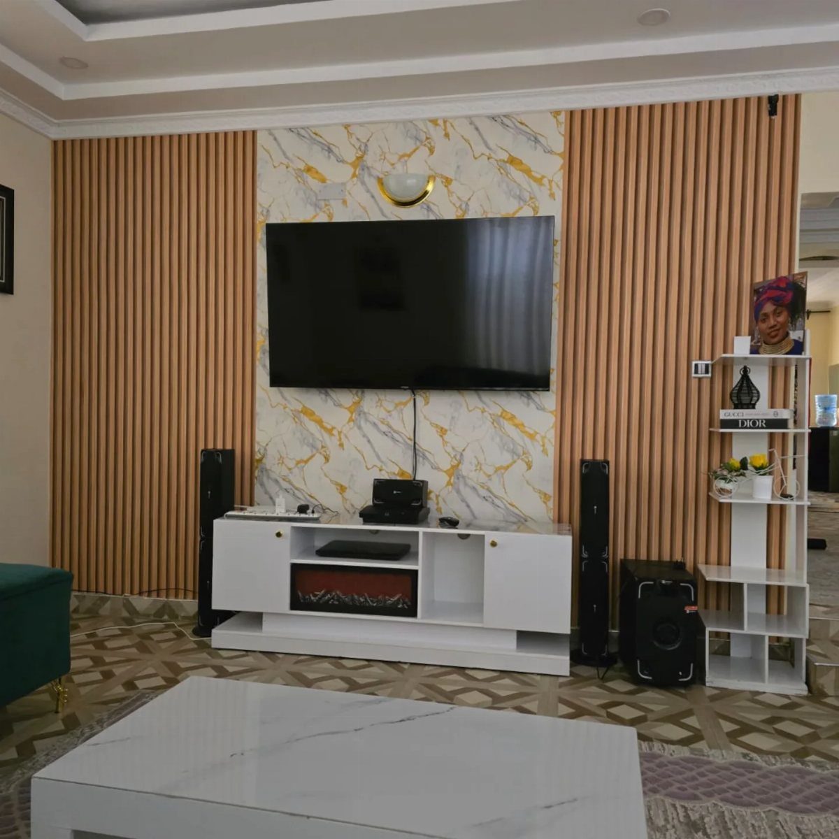 Wall-mounted TV with marble-patterned back panel, wooden slats, and white modern console.