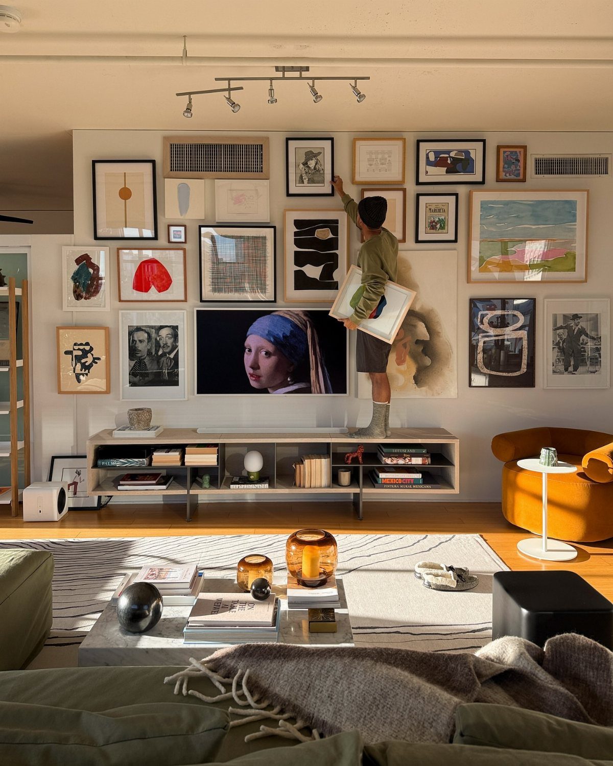 Gallery wall with numerous framed artworks surrounding a television in a modern living room.