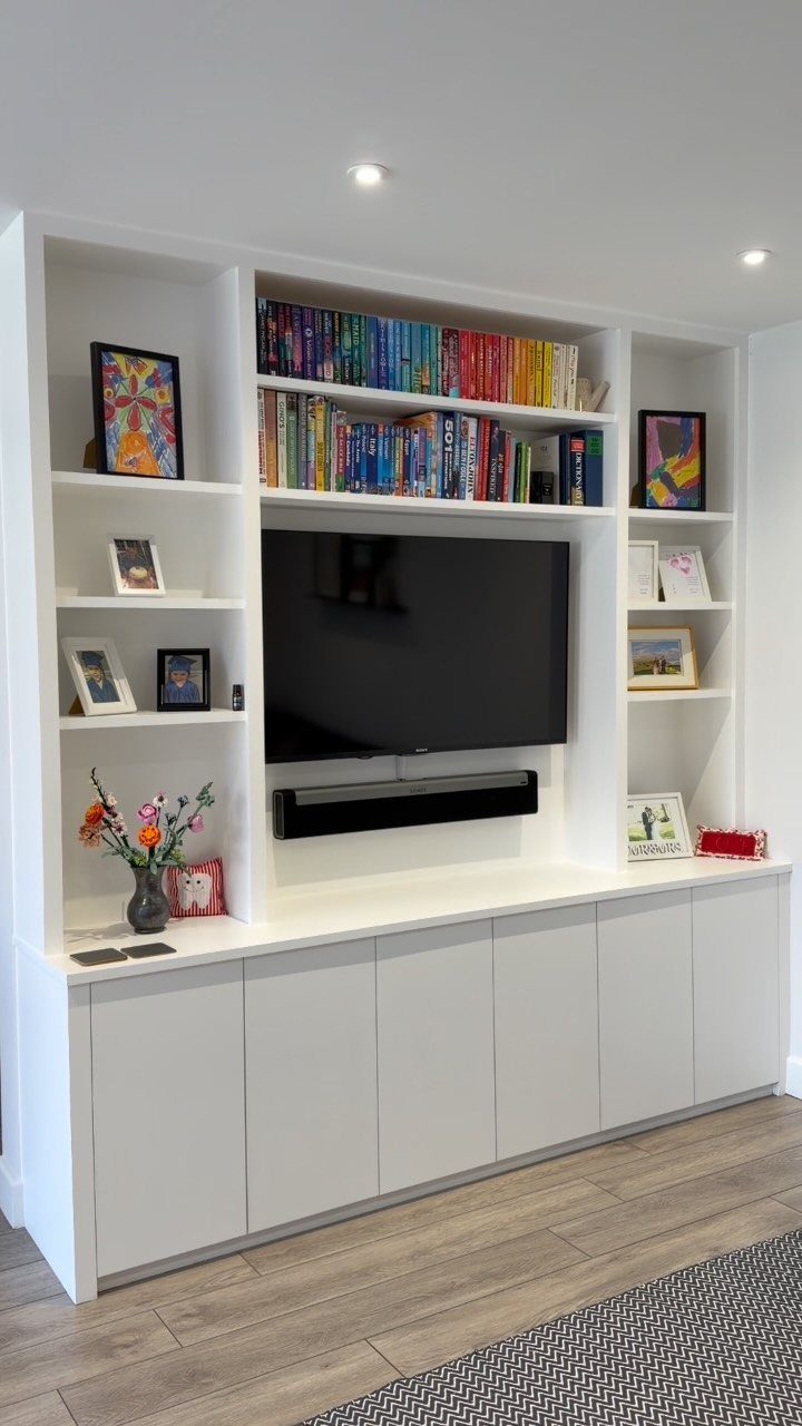 White built-in entertainment center with closed cabinets underneath a wall-mounted television.