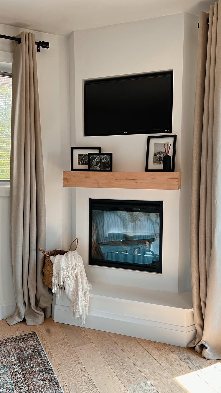 Wall-mounted TV above a wooden mantel and fireplace in a bright living room.