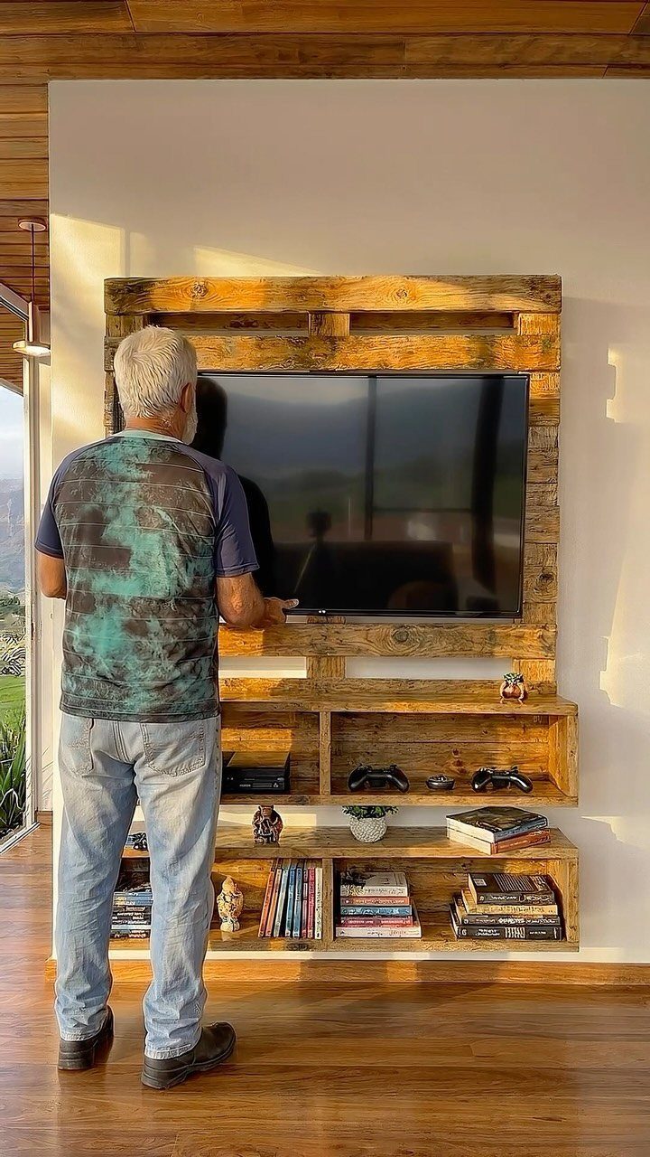 Rustic wooden shelving unit and TV frame with a man standing in front.